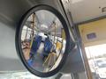 A 2017 Chevrolet Express bus interior reflecting in a convex mirror showing rows of blue seats and yellow poles