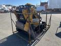 A yellow and black 2024 AGT KTT23 Mini Skid Steer secured in a metal frame with tracks and a front bucket attachment