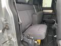 The image shows the rear interior seating of a 2014 Ford F-150 with black fabric upholstery and a spacious layout