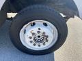 A close-up view of a tire mounted on a white rim with multiple lug nuts showing signs of wear and rust