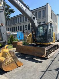 A 2009 John Deere 135 D excavator with a yellow and gray body and a large bucket attachment in the front