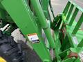 A 2003 John Deere 790 tractor showing the front loader attachment and green hydraulic components along with a warning label on the side
