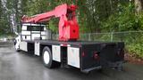 A white 2010 International 4300 truck with an extended red crane and a flatbed with metallic compartments on the sides