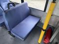 A blue vinyl bench seat with a handle on the side located inside a vehicle with a yellow pole beside it