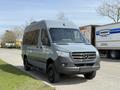 A gray 2019 Mercedes-Benz Sprinter van parked on a pavement with a streamlined design and black wheels