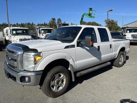 A white 2013 Ford F-250 SD with a crew cab and off-road tires parked at a commercial location