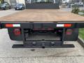 A 2012 Ford F-550 flatbed truck viewed from the rear with a wooden bed and dual taillights