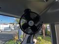 A black circular fan mounted on the ceiling of a 2015 Chevrolet Express with a blue and white logo in the center