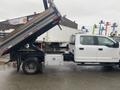 A 2021 Ford F-550 truck with a dump bed raised, showing its cargo area and side storage compartment