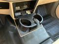 A black cup holder in the center console of a 2013 Ford F-450 SD featuring a two-cup design with a textured surface underneath