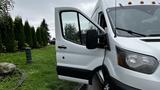 A white 2017 Ford Transit van with the driver's door open, revealing the interior and side mirror