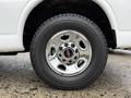 A chrome wheel with a GMC logo mounted on a rugged tire of a 2009 Chevrolet Express