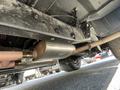 A 1962 Ford F-100 with visible exhaust components including a shiny muffler and exhaust piping under the vehicle