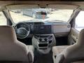 Interior view of a 2012 Ford Econoline with two front seats a dashboard featuring a radio and climate controls and cup holders between the seats