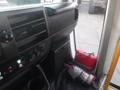 Interior view of a 2016 Chevrolet Express showing the dashboard with controls and a fire extinguisher next to a red bag on the floor