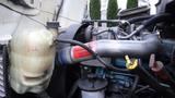 A close-up of the engine components of a 2005 International 4300 including a coolant reservoir a metal pipe and various hoses and caps