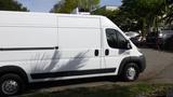 A white 2017 RAM Promaster van with a high roof and ventilation unit on top parked with its side facing the viewer