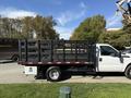 A white 2016 Ford F-350 Super Duty truck with a flatbed and a black metal rack on the back