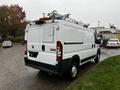 A white 2018 RAM Promaster van with a ladder rack on the roof and rear doors partially open