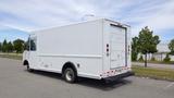 A white 2011 Ford Econoline delivery truck with a boxy shape and a rear roll-up door parked on a lot