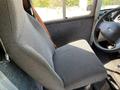 A gray upholstered driver's seat of a 2011 Ford Econoline with a black steering wheel visible in the foreground