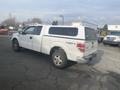 A white 2009 Ford F-150 with a truck bed cover and off-road tires parked in a lot