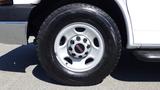 A close-up of a white 2015 GMC Savana wheel with five lug nuts and a red GMC logo on the center cap