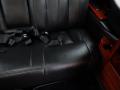 Interior view of a black leather seat in a 2008 Cadillac Limousine featuring seat belts and wooden trim