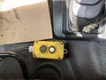 A yellow control box with two buttons and a connected black cable on a textured surface inside a vehicle