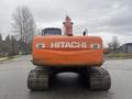 A 2006 Hitachi ZX200LC excavator with an orange body and black tracks positioned head-on facing the viewer