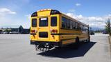 A yellow 2014 International 3000 school bus viewed from the rear with black wheels and a chain device attached to the back