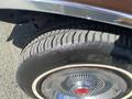 A close-up of the tire and wheel of a 1982 Mercury Grand Marquis showing detailed tread pattern and chrome hubcap with a red center emblem