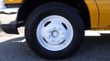 A close-up view of a white steel wheel with six lug nuts mounted on a 2015 Ford Econoline tire