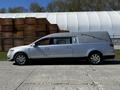 A silver 2013 Lincoln MKT hearse with a custom gray top and elongated body design parked on a gravel surface