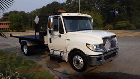 A white 2014 International TerraStar truck with a flatbed and black toolboxes on the side parked at an angle