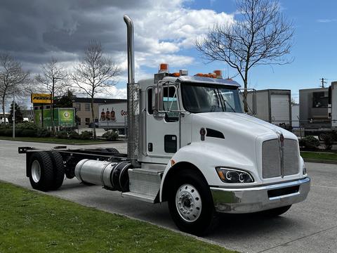 A white 2014 Kenworth T370 truck with a shiny chrome grille and a tall exhaust stack parked on the street