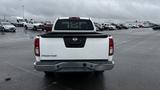 A white 2016 Nissan Frontier truck viewed from the rear with the tailgate down and the word FRONTIER displayed on the back