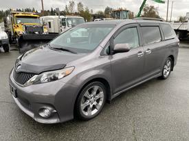 A gray 2013 Toyota Sienna minivan with a sleek design and alloy wheels parked on a wet surface