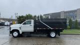 A white 2021 International CV515 dump truck with a black dump bed parked on a wet surface