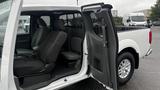 A white 2016 Nissan Frontier with an open passenger door showcasing the interior seating and cabin layout