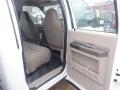 Interior view of a 2009 Ford F-450 SD showing the front and back seats with beige upholstery and an open door