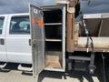 A 2010 Ford F-550 with a partially open metal storage compartment on the side revealing empty shelves inside