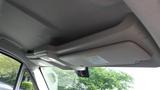 A beige sun visor mounted on the ceiling of a 2017 RAM Promaster with a warning label attached