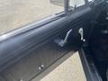 Interior door panel of a 1966 Ford Mustang featuring a black textured design with a chrome door handle and window crank