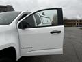 A 2019 Chevrolet Colorado with an open driver's side door showcasing a white exterior and black accents