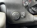 Close-up of the dashboard controls in a 2015 Chevrolet Express with a dial for headlights and a switch for driving lights