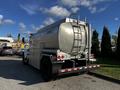 A 2013 Kenworth T370 diesel fuel truck with a large silver tank and a rear ladder parked in a lot