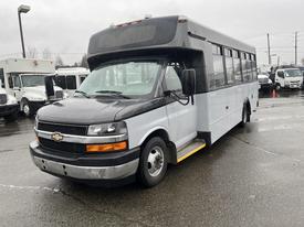 A 2017 Chevrolet Express bus in a two-tone black and white color scheme with prominent headlights and large windows on the side