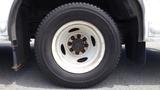 Close-up of a white tire mounted on a 2011 Ford Econoline featuring a rugged tread pattern and visible wheel rim with rust spots