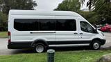 A 2017 Ford Transit van with a long body and high roof in white color parked on grass